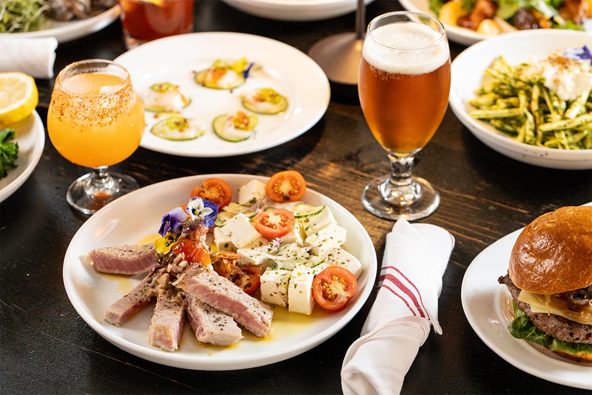 A table spread of small plates, burgers and drinks at Harper's