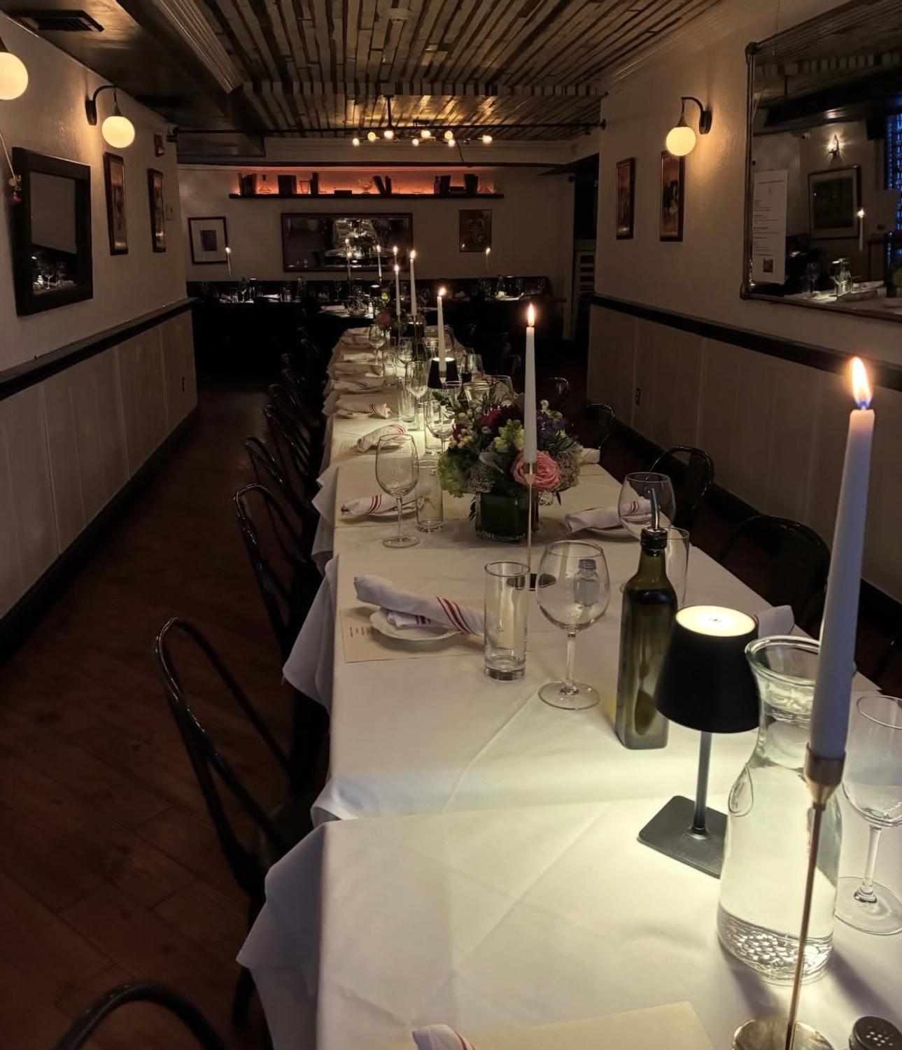 A long candlelit table set with flowers for a private party at Harper's