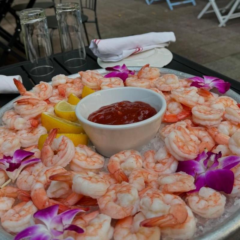 A chilled jumbo shrimp cocktail platter with lemon and orchids at Harper's